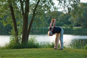 Senior man doing yoga stretch outside 
